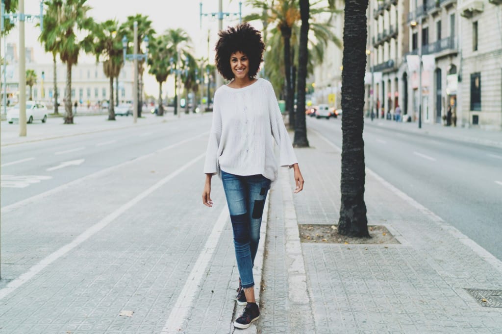 Full length portrait of female in casual clothing walking down the street with confidence