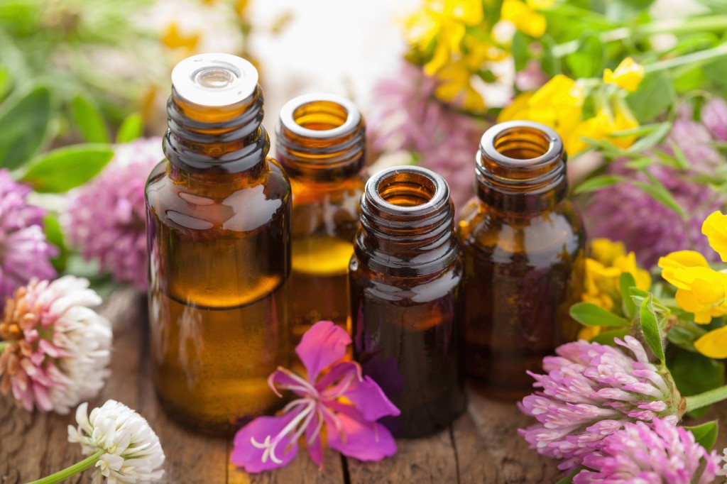 Bottles of essential oils amongst flowers and herbs