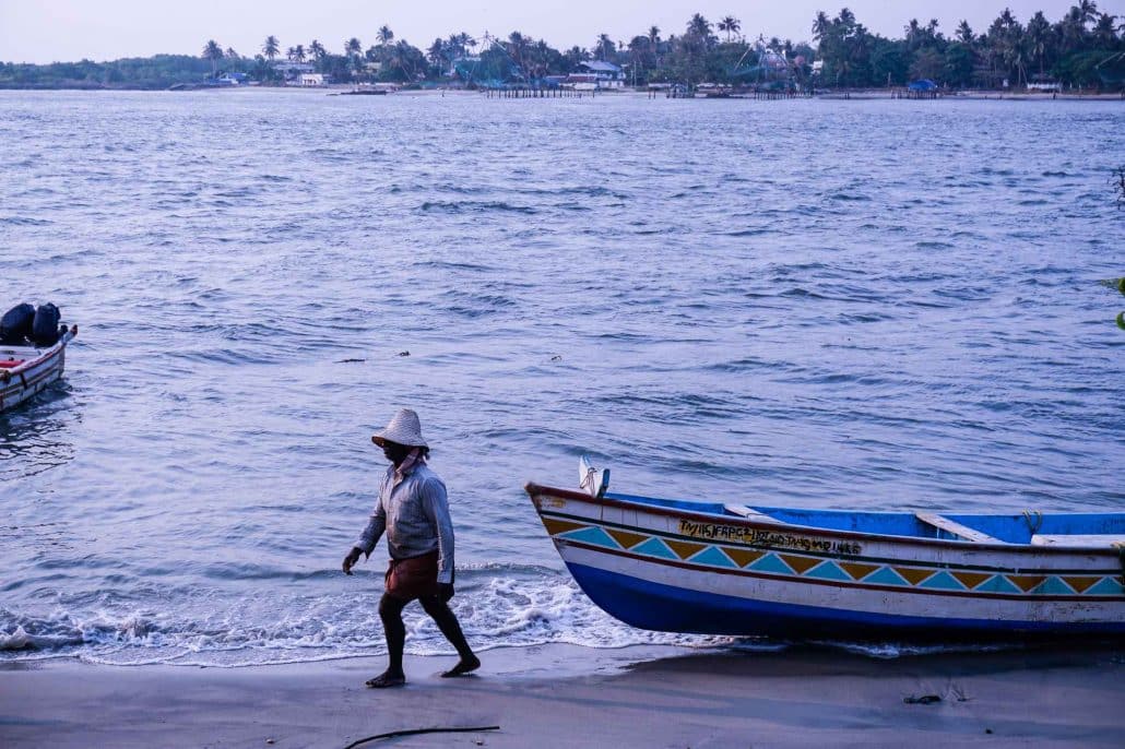 Fisherman in Kochi walking next to his boat on the shore.