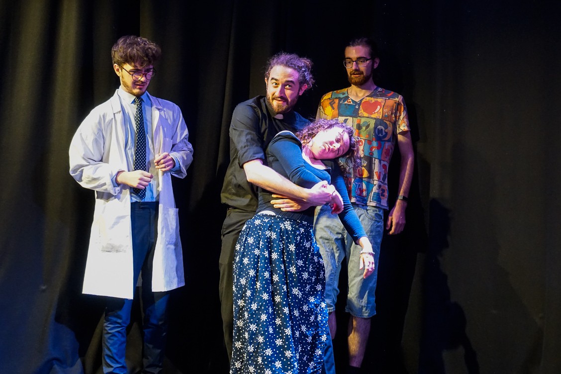 Performers in the Holy Sh*t play in a scene holding a dead woman