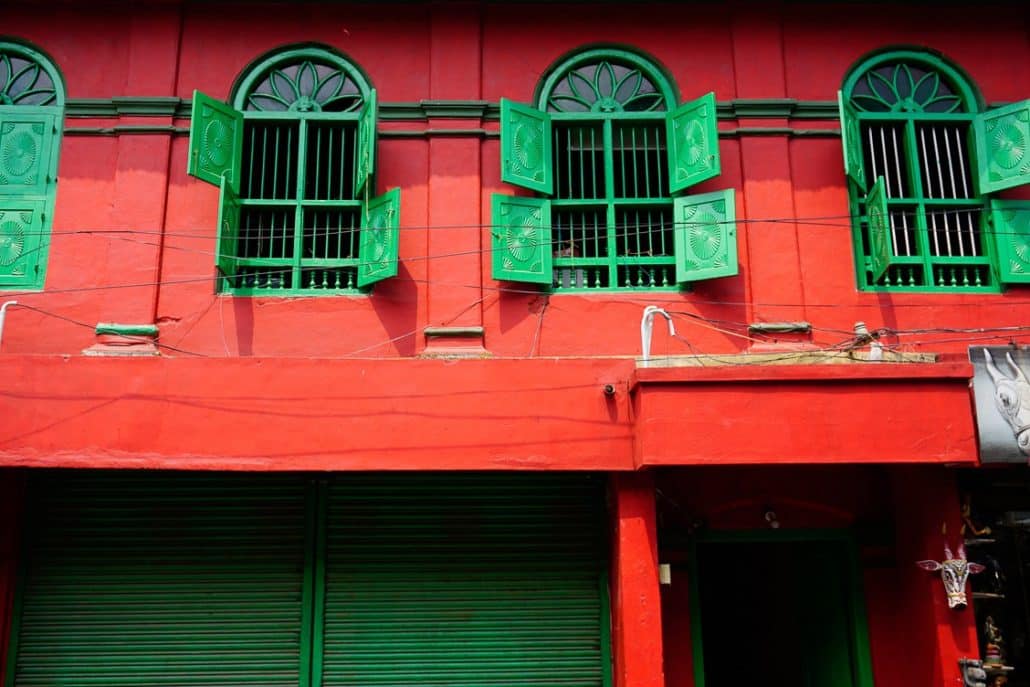 Red building with green windows and shutters as well as a matching green door.