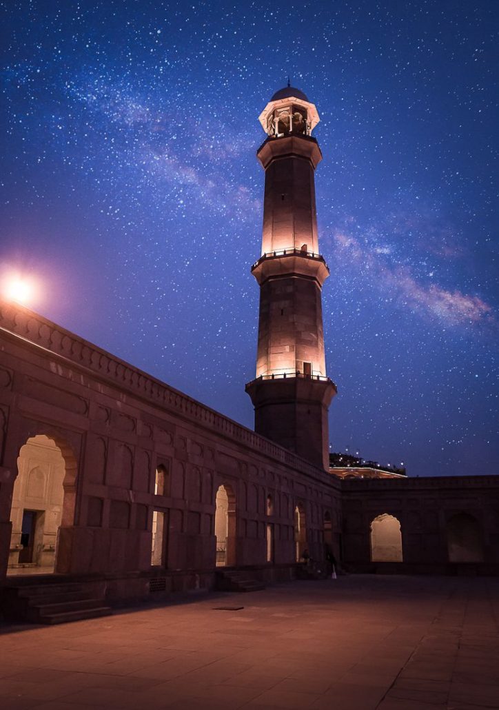 Illuminated minaret at Badshahi Mosque at night with the milky way seen behind it