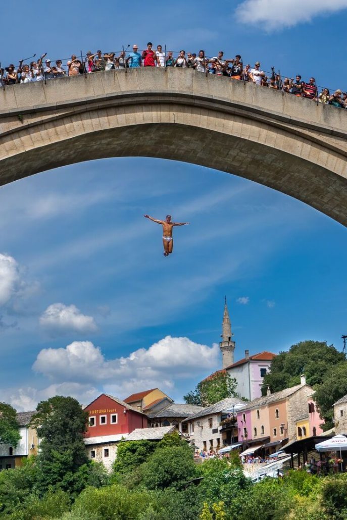 Photo of a man in a swimming outfit jumping off the famous Mostar Bridge