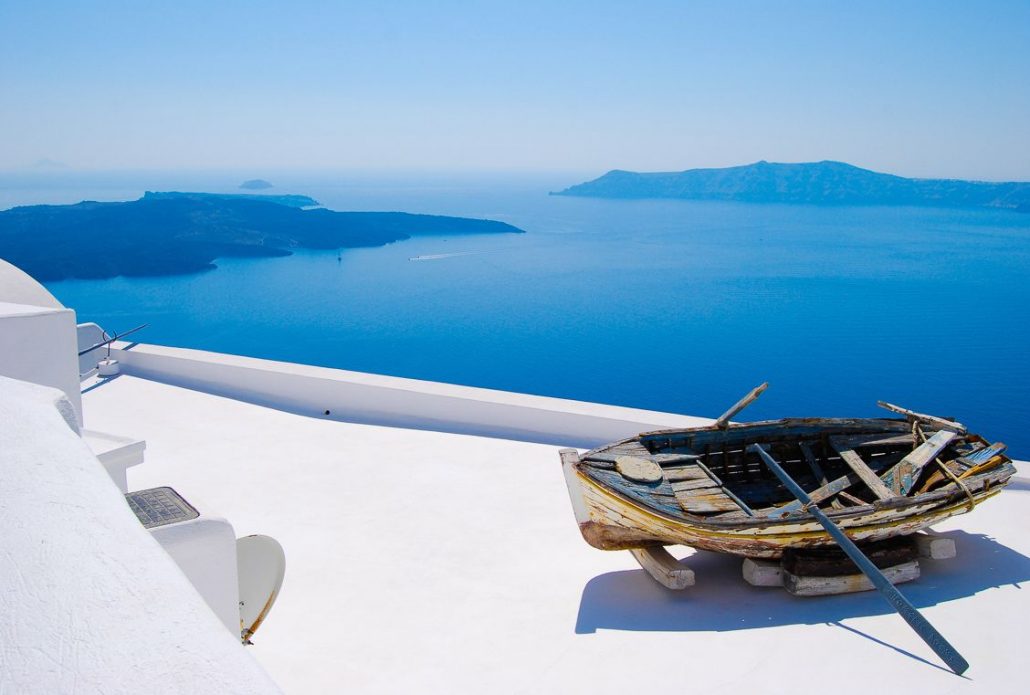 Photo of an old, decrepit boat on a crisp white balcony in Greece