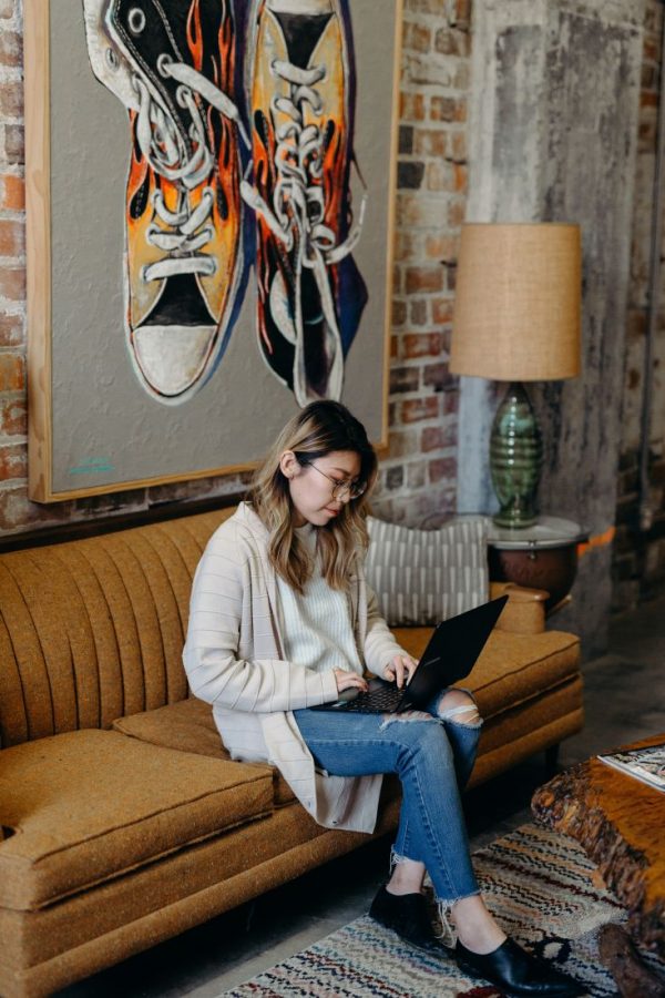 Girl working on her laptop while sitting on a brown couch