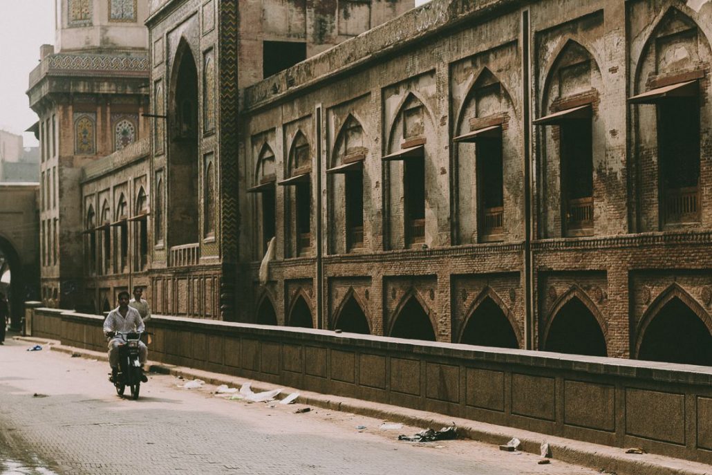 Man riding a motorbike next to an abandoned building in Lahore, Pakistan