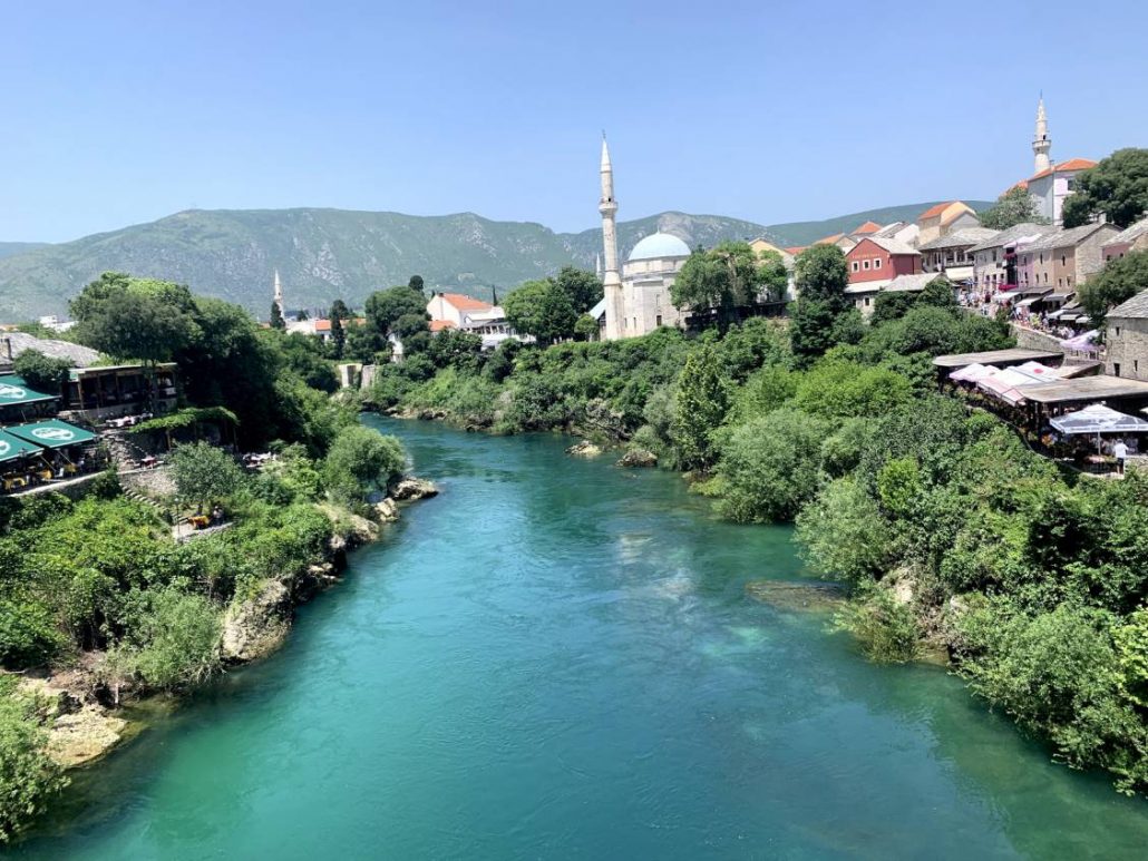 Photo taken from the old bridge in Mostar of the city sitting along the right side of the river