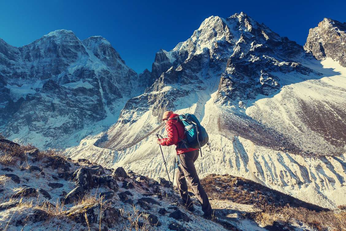 Photo of a person trekking in Nepal atop snow-capped mountains