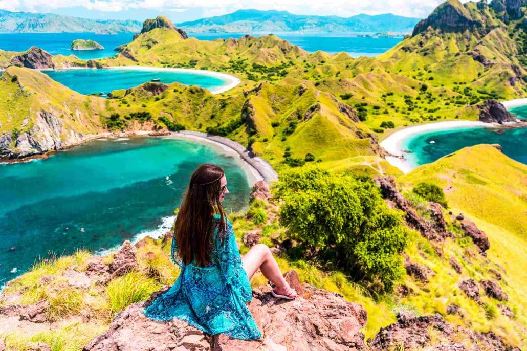 Solo female looking out across Komodo National Park in a beautiful blue dress which matches the colour of the sea