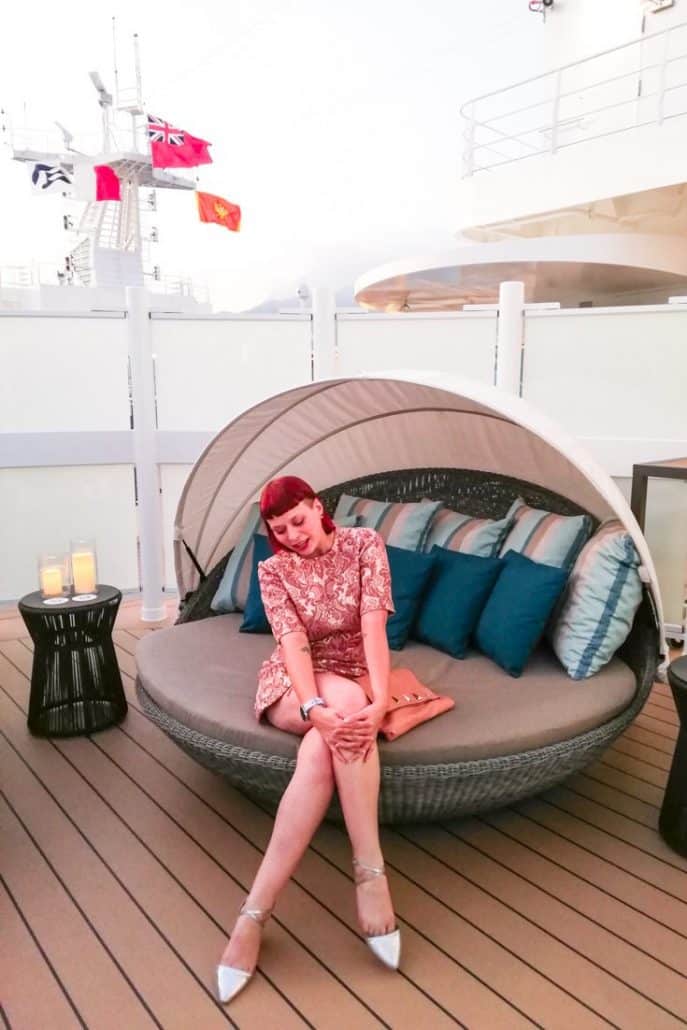 Photo of Alice sitting on a circular couch on the balcony of the Sky Suite