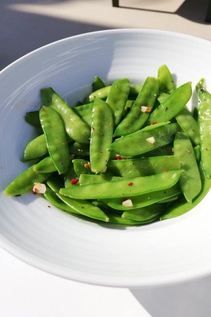 Photo of a white bowl filled with cooked edamame that have been garnished with some spices