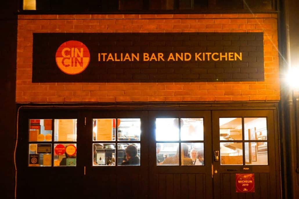 The outside of Cin Cin Restaurant in Brighton, with red brick walls and black garage doors