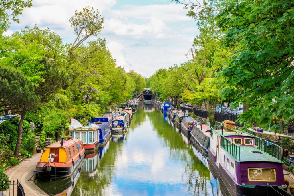 Beautiful boats along Little Venice canal on a sunny day with green trees and blue skies
