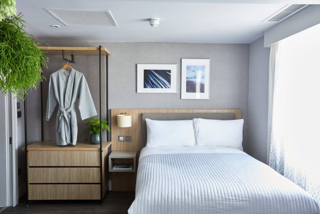 Beautifully crisp and clean room in Inhabit Hotel with fresh white linen and calming grey walls with wooden furniture