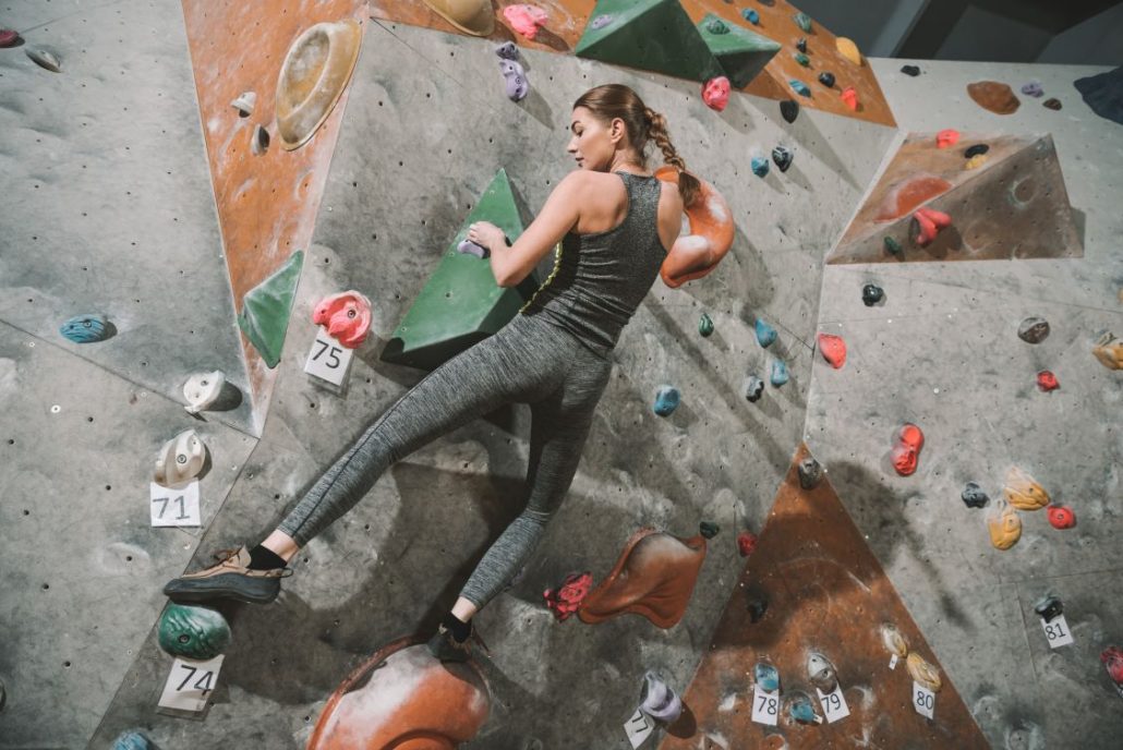 Fit and healthy women climbing up a colourful climbing wall in London