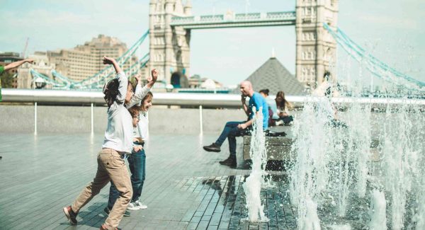 Kids playing in London with water fountains in front of Tower Bridge during a London visit with kids