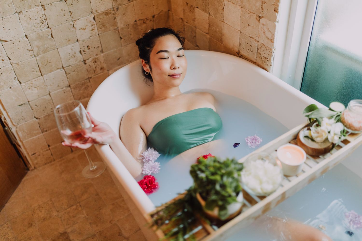 Asian language enjoying luxury travel in the bathtub with a glass of wine