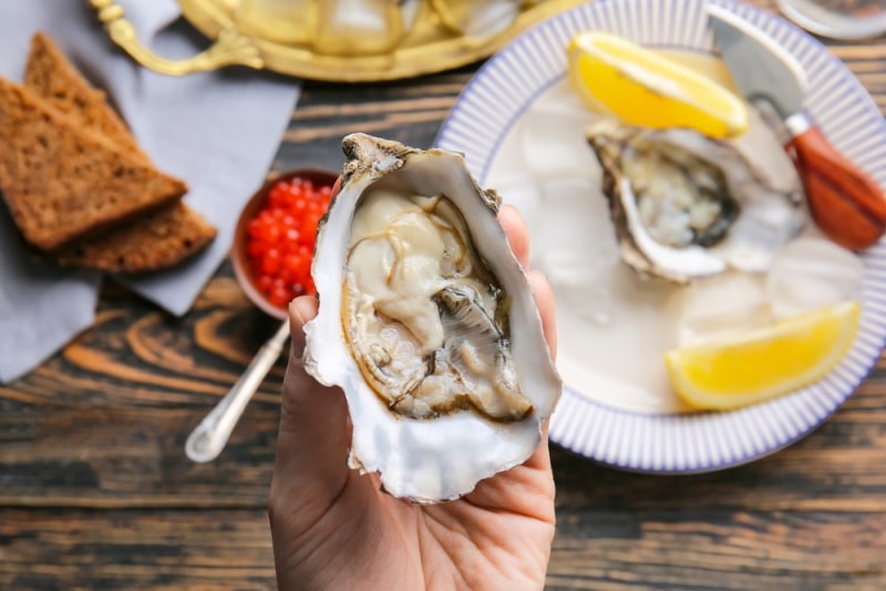 Close up of a woman eating oysters with lemon