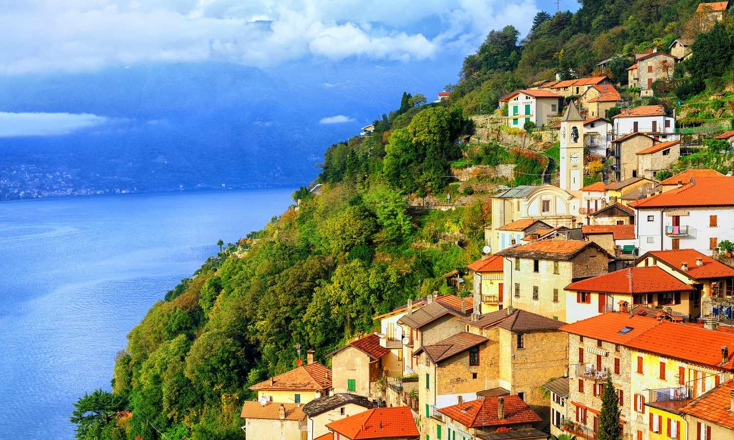 A small town on a hill on Lake Como in Northern Italy with coloured buildings with red roofs