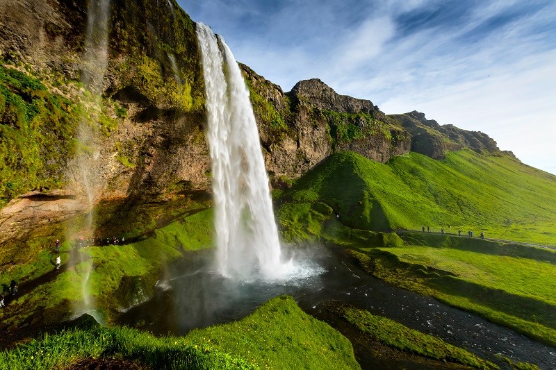 A view of Seljalandsfoss waterfall dramatically dropping down against a lush green landscape.