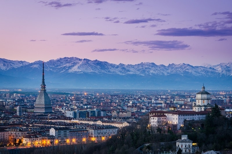 Stunning Turin at night with a purple sunset sky behind it and the Alps mountains in the background